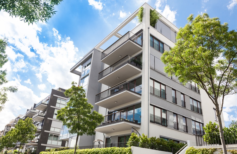 A white and gray apartment building on a sunny day.